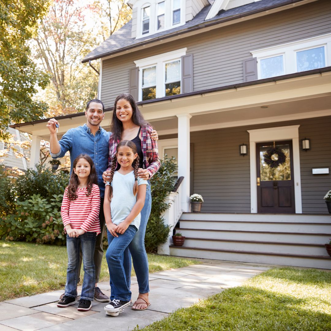 Family smiling outside of their new home