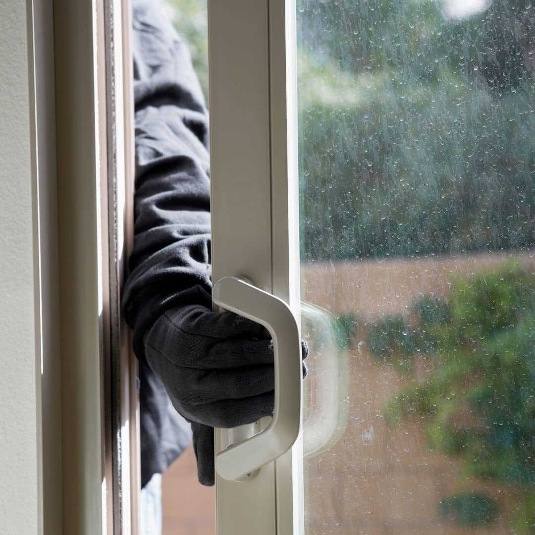 Thief breaking into a home through a sliding glass door
