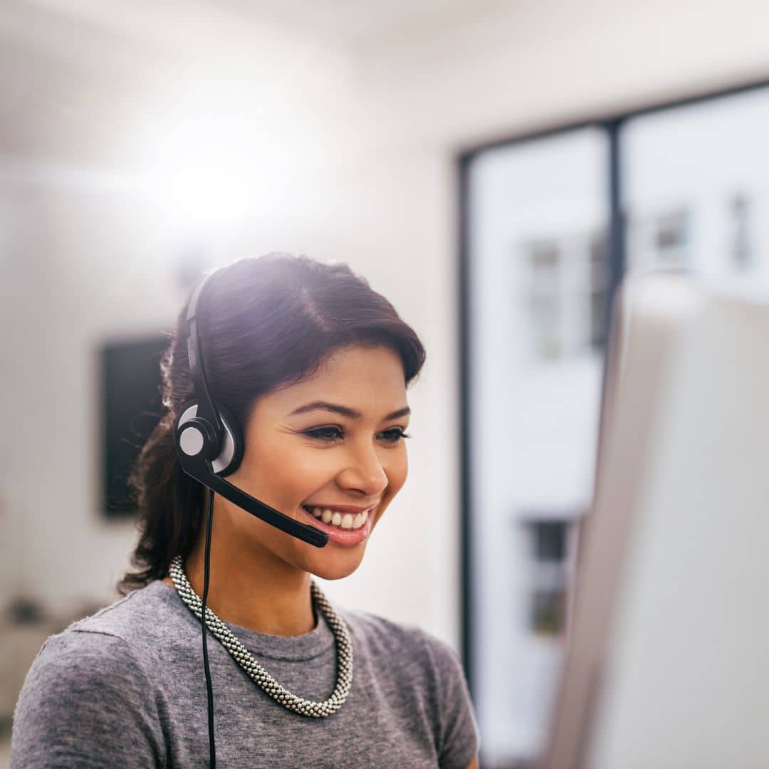 a business woman wearing a phone headset and using a desktop