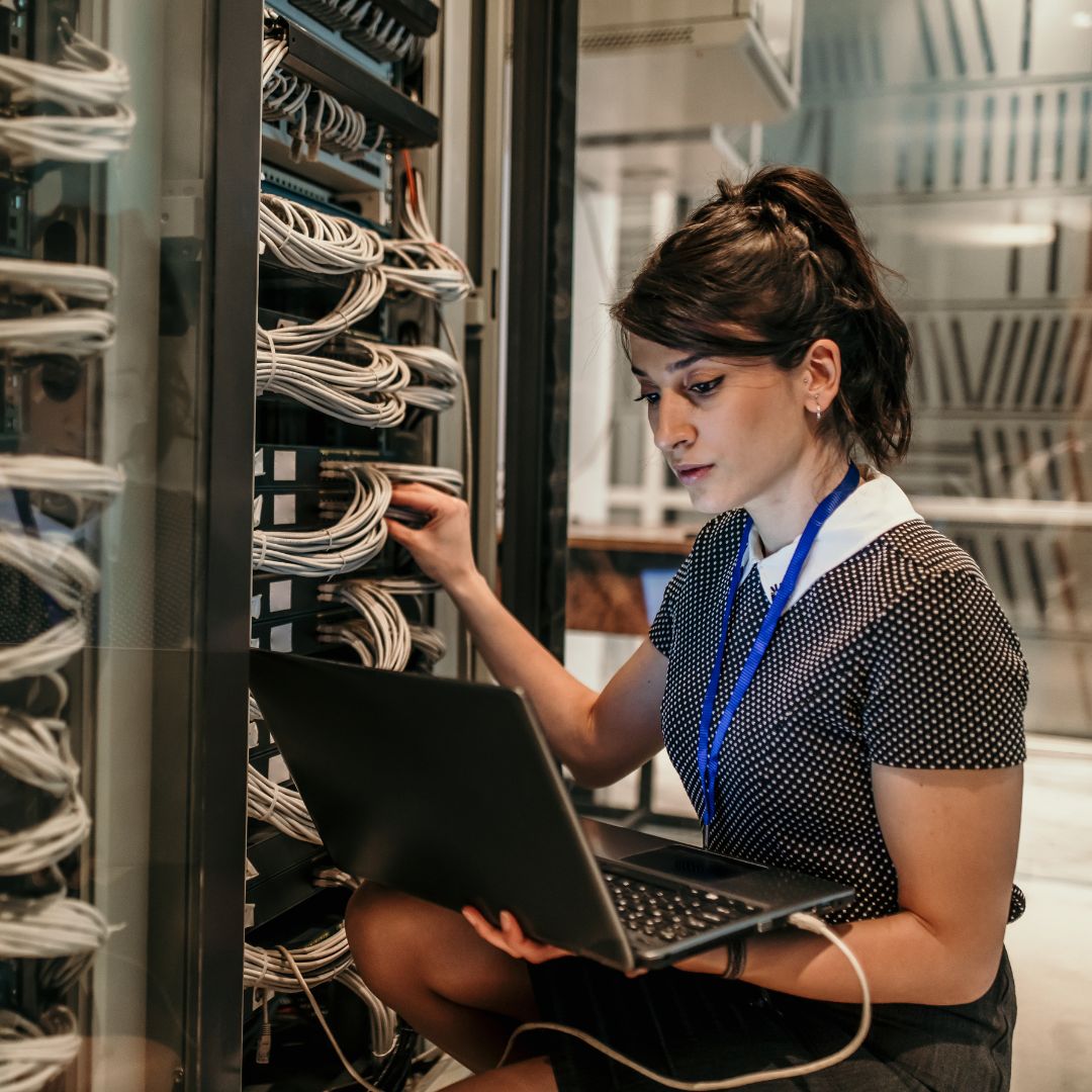 an IT woman using a laptop in a server room