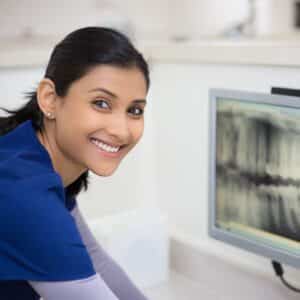 Dental professional looking at x-rays on a computer screen