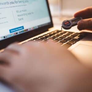 close up of hands typing on laptop keyboard using code keeper tag