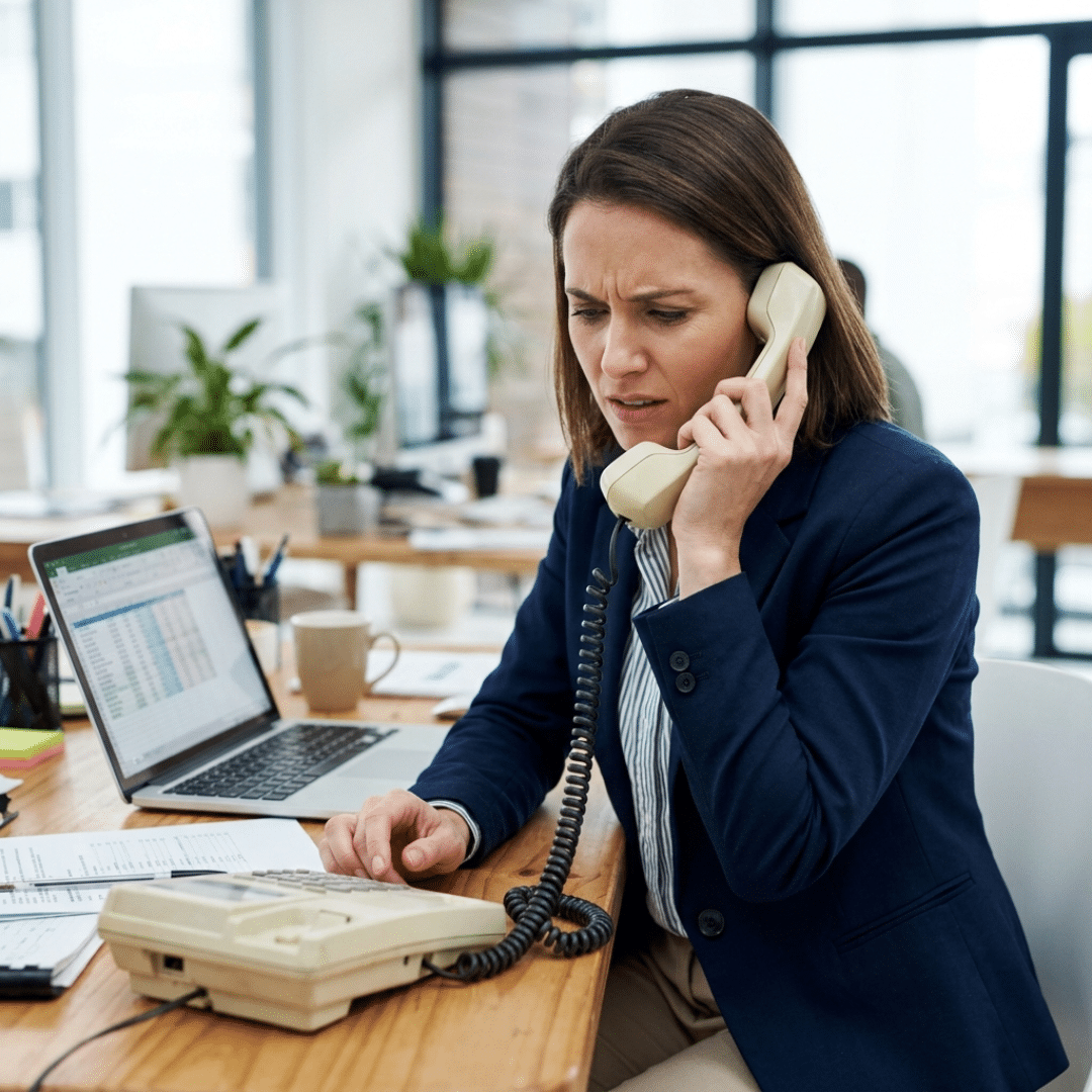 Frustrated employee using an outdated legacy corded phone system.